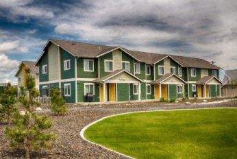 a green house with a yard and a cloudy sky